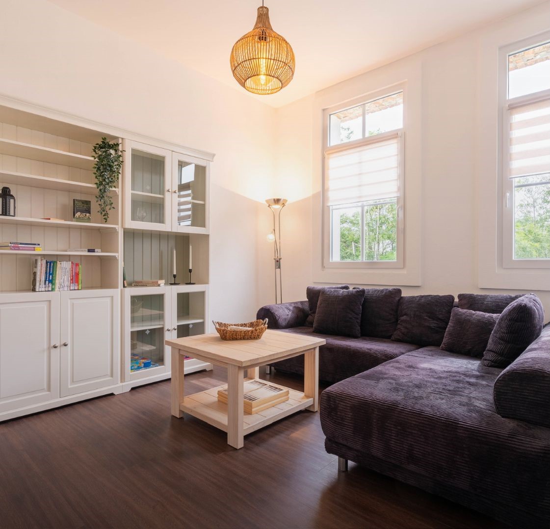 Helles Wohnzimmer mit großer Eckcouch, Holztisch und Bücherregal.